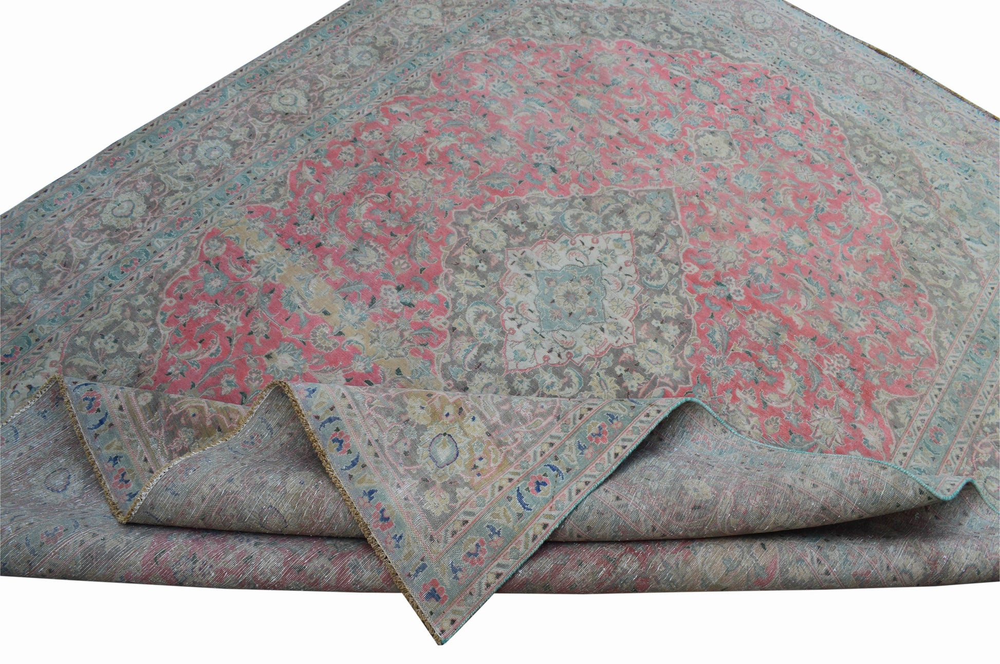 A vintage Persian Kashan rug featuring intricate floral patterns in pink, grey, and blue tones.