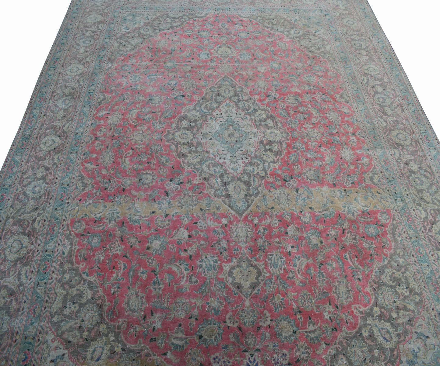 A vintage Persian Kashan rug featuring intricate floral patterns in pink, grey, and blue tones.