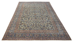 A vintage Persian Kashan rug featuring intricate floral patterns in blue and beige tones.