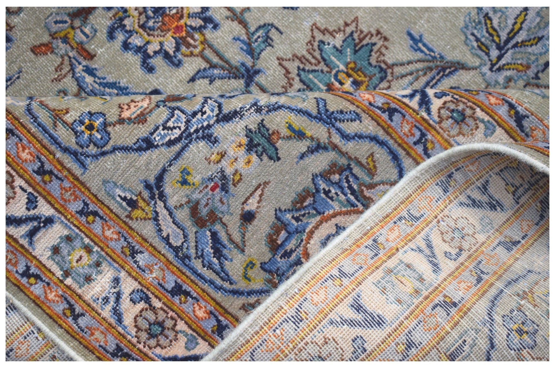A vintage Persian Kashan rug featuring intricate floral patterns in blue and gold on a grey field.
