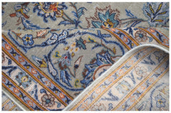 A vintage Persian Kashan rug featuring intricate floral patterns in blue and gold on a grey field.