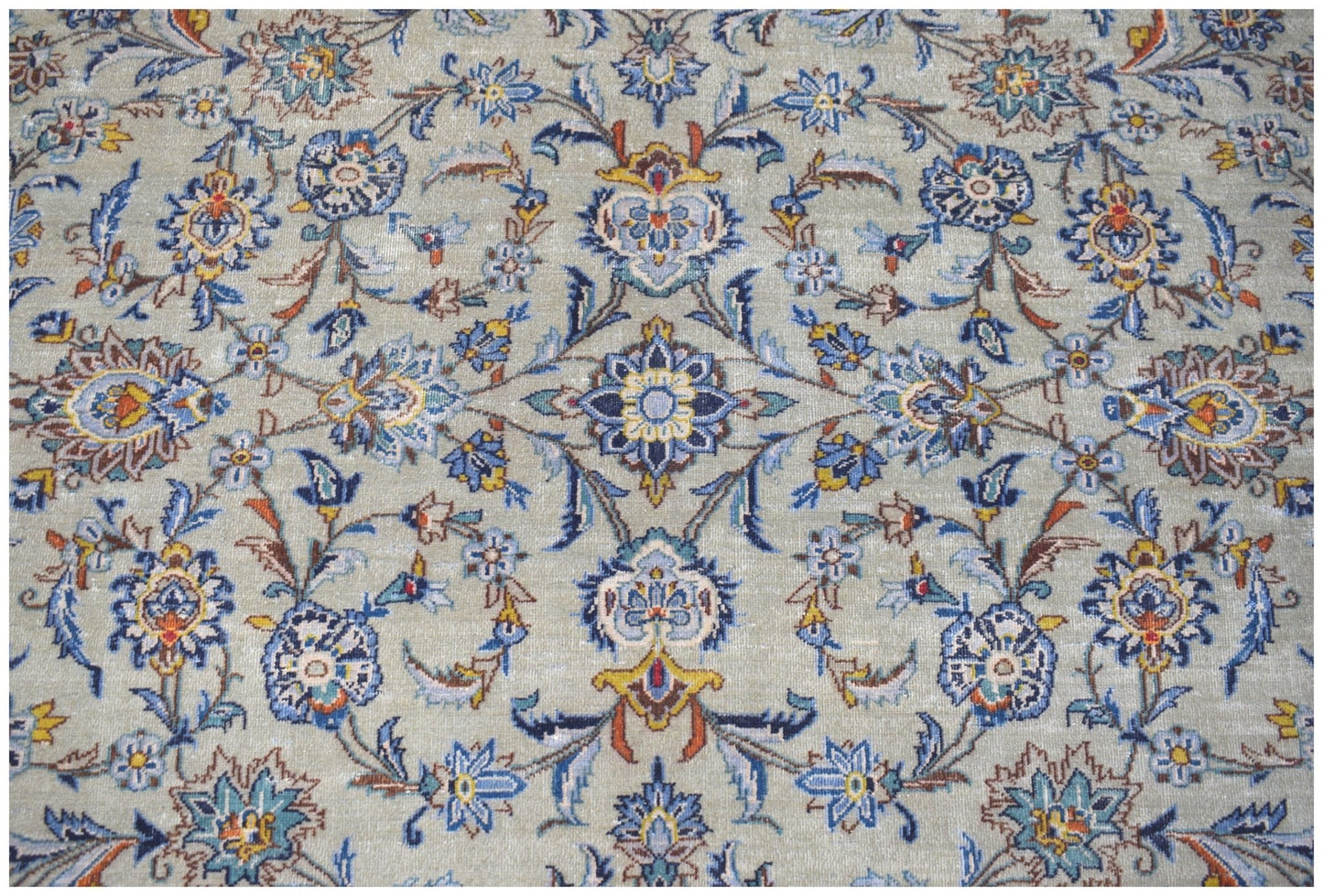 A vintage Persian Kashan rug featuring intricate floral patterns in blue, gold, and cream tones.
