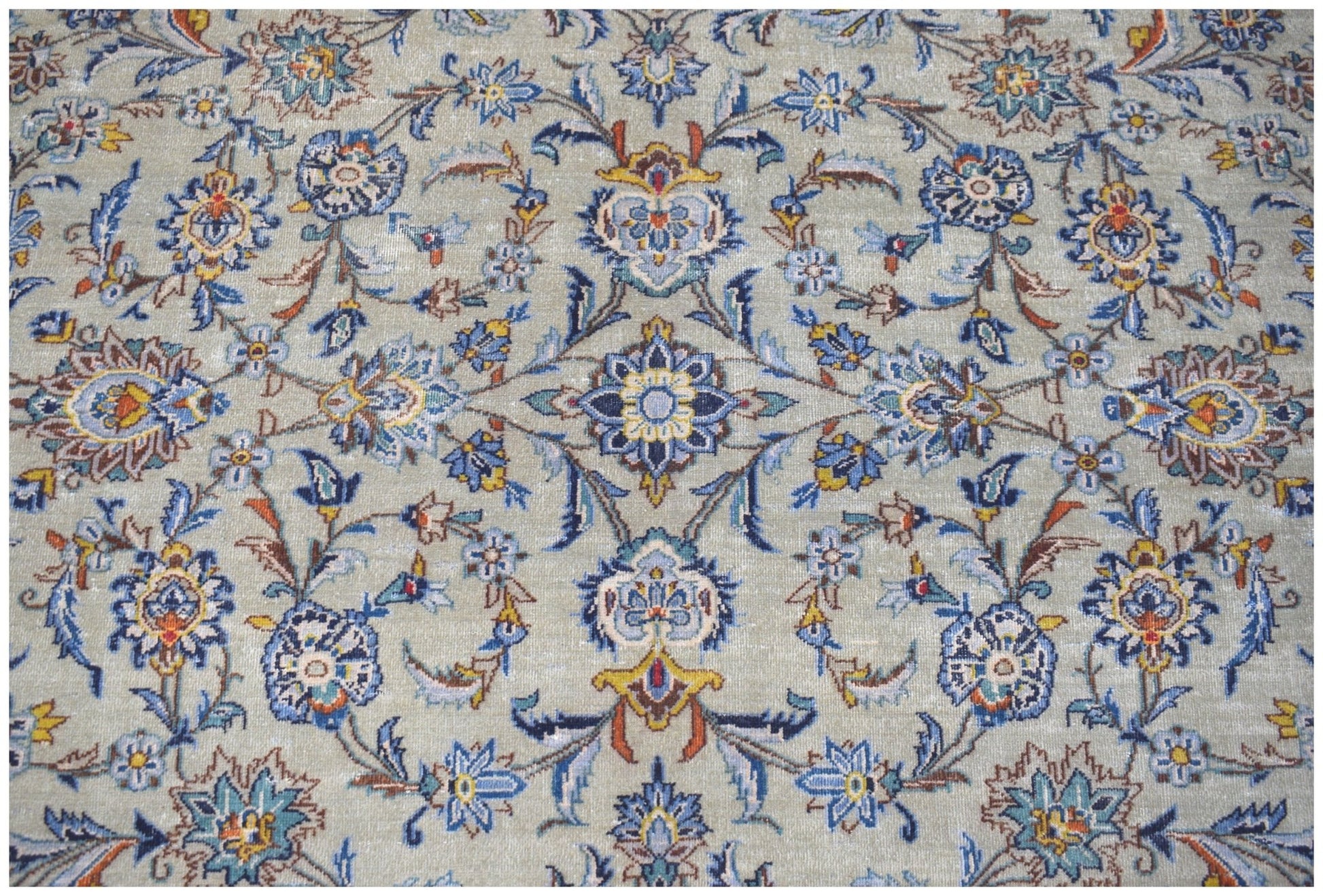 A vintage Persian Kashan rug featuring intricate floral patterns in blue, gold, and cream tones.