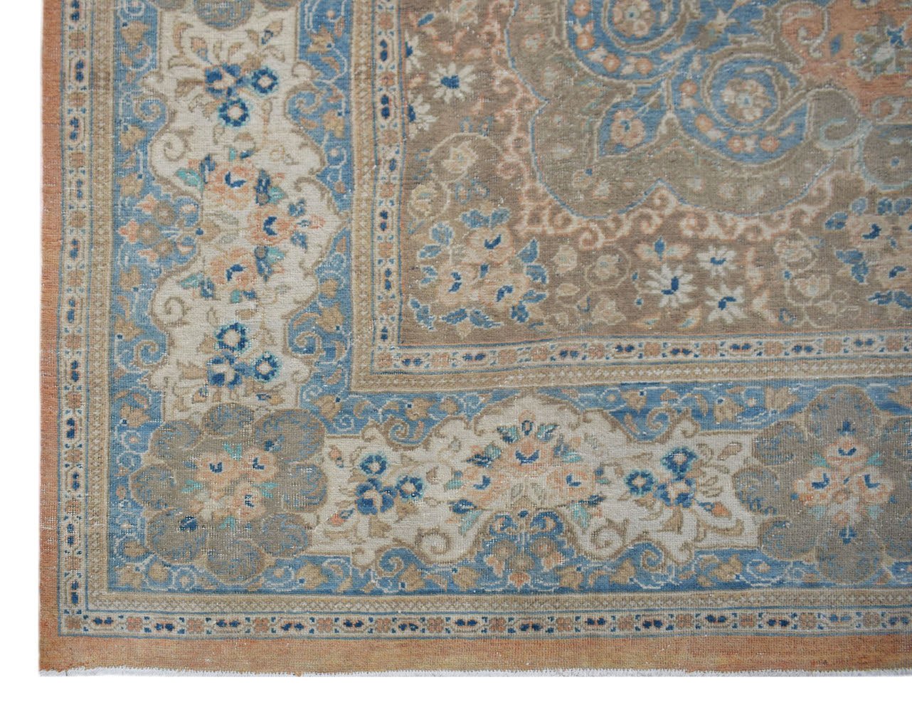 A vintage Persian Kashan rug featuring intricate floral patterns in blue, beige, and terracotta.