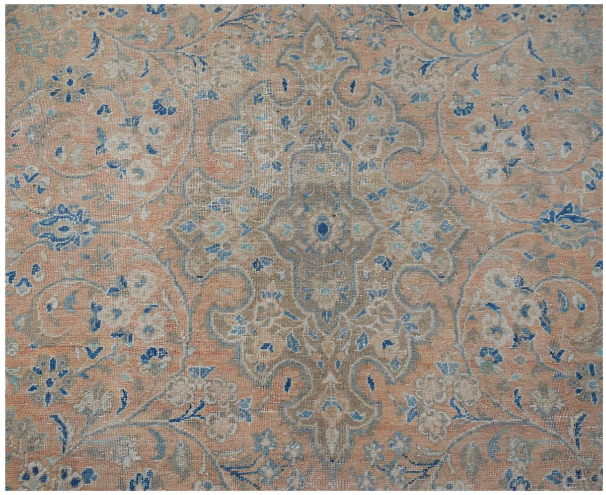 A vintage Persian Kashan rug featuring a central floral medallion in muted peach and blue tones.