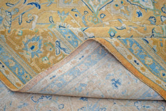 A vintage Persian Kashan rug with a gold and blue floral medallion pattern folded to show the back.