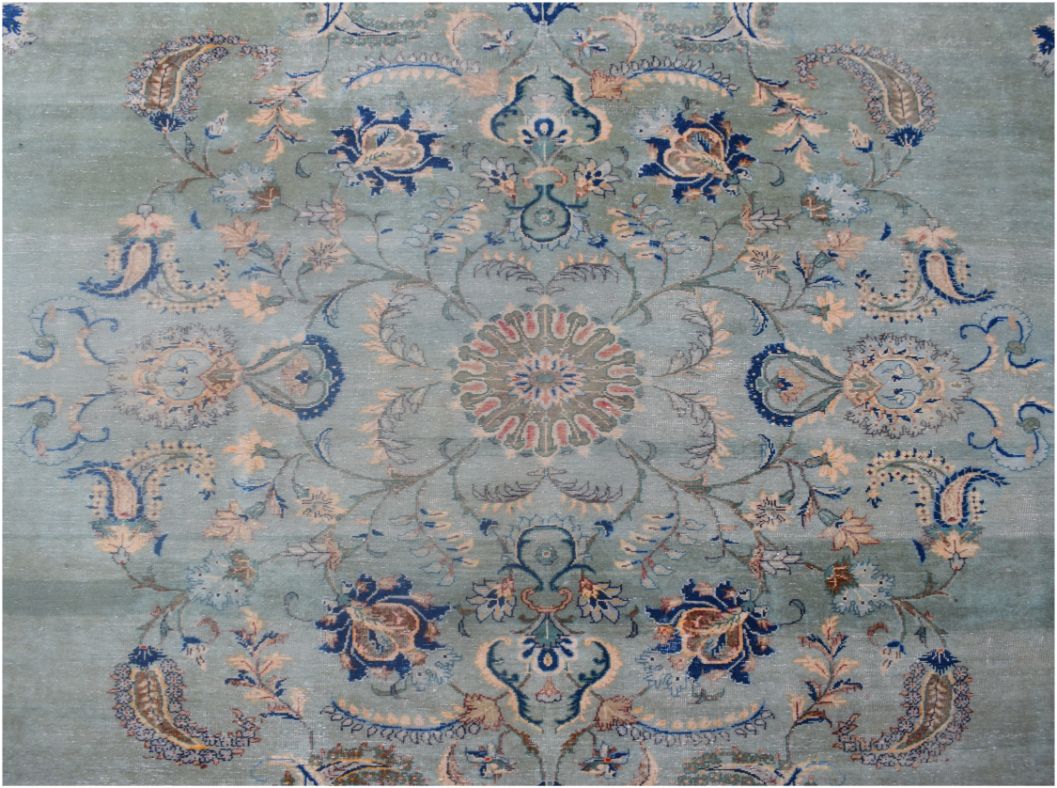 A vintage Persian Kashan rug featuring a central floral medallion on a light blue field.