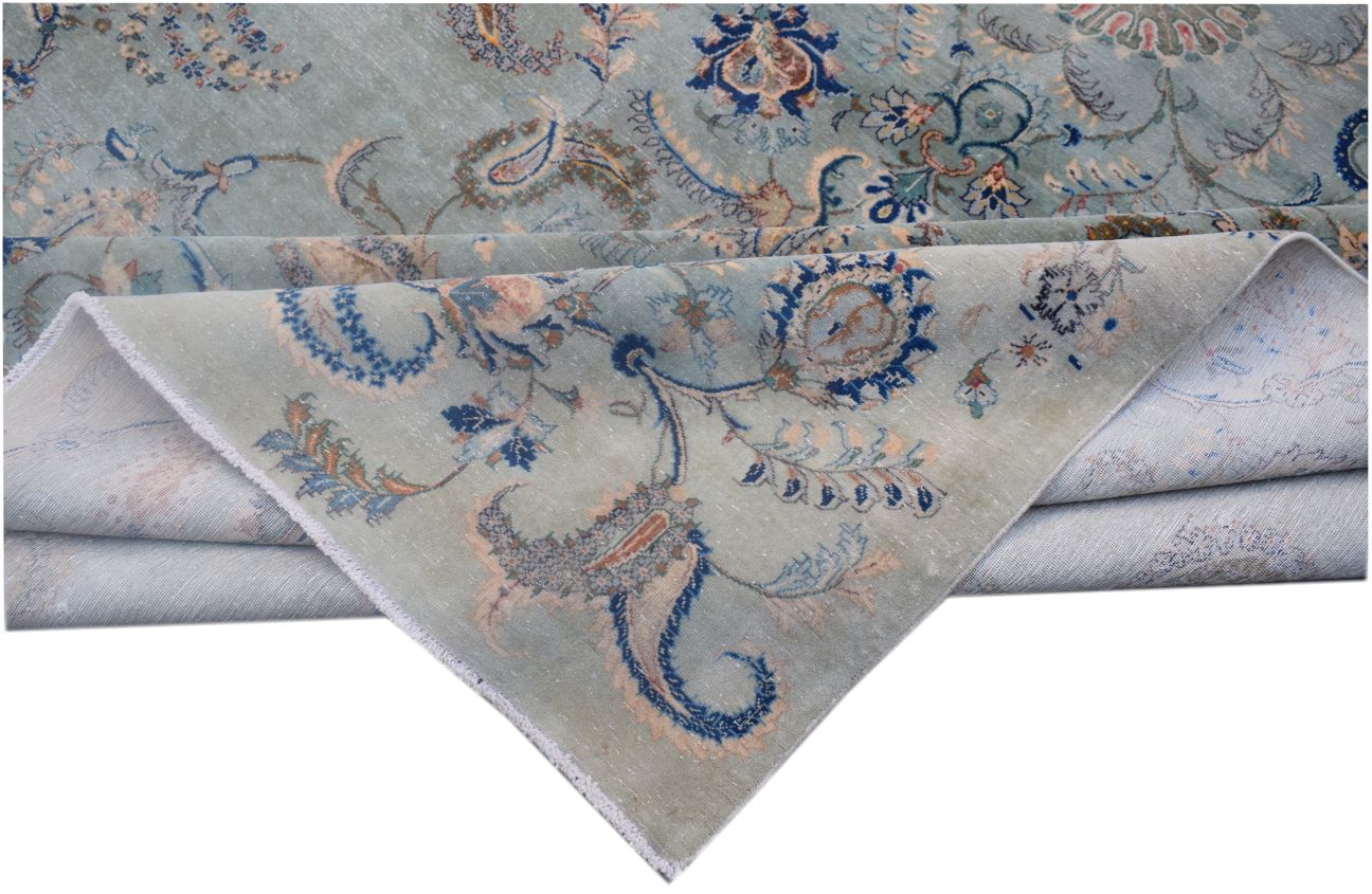 A vintage Persian Kashan rug featuring intricate floral patterns in blue and beige tones.