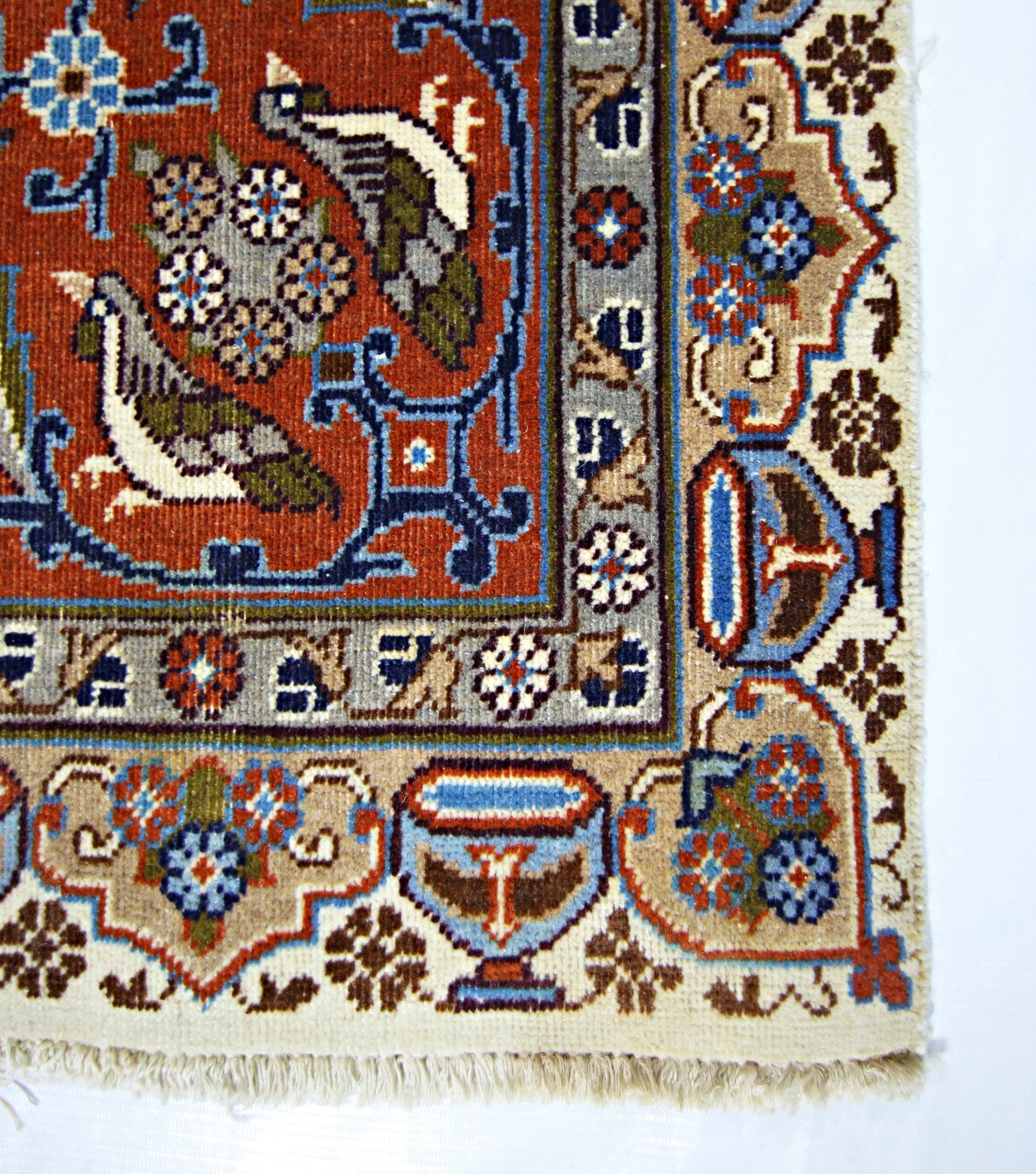 A corner view of a vintage Persian Kashmar rug featuring intricate bird and floral motifs.