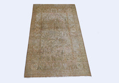 A vintage Persian Kerman rug featuring a faded floral medallion design in soft, neutral tones.