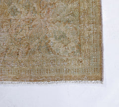 A vintage Persian Kerman rug featuring a faded, intricate floral pattern in muted earth tones.