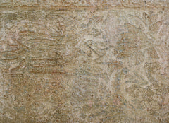 A vintage Persian Kerman rug featuring a faded, intricate floral pattern in neutral tones.
