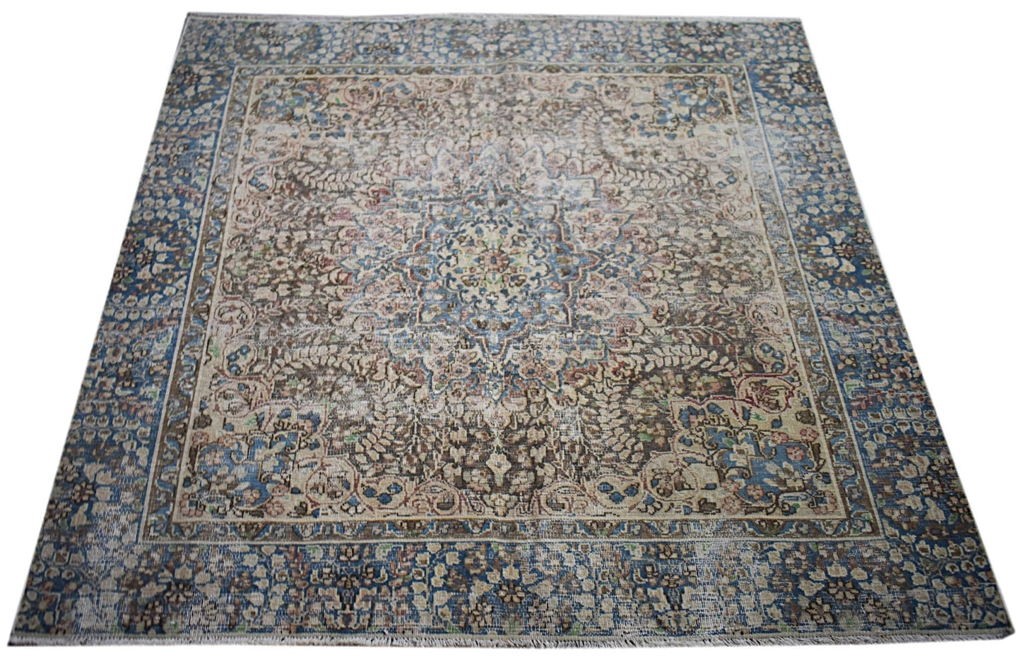 A vintage Persian Kerman rug featuring an intricate central medallion and floral patterns in blue.