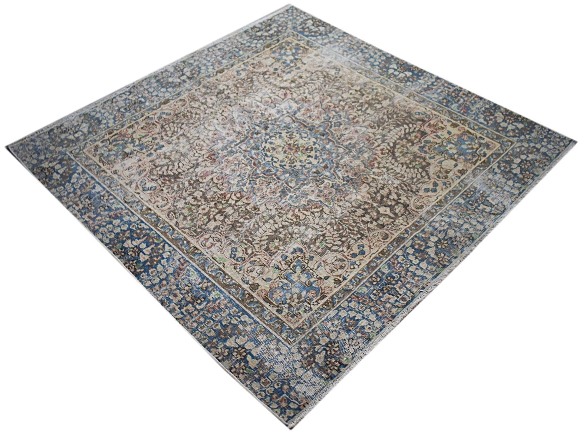 A vintage Persian Kerman rug featuring an intricate floral medallion in blue and beige tones.