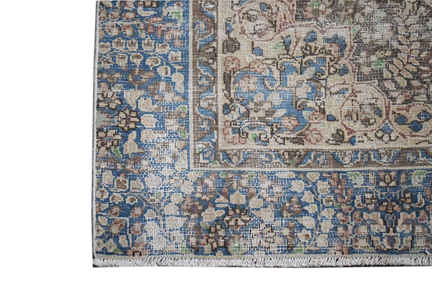 A vintage Persian Kerman rug featuring an intricate floral pattern in blue, brown, and cream tones.