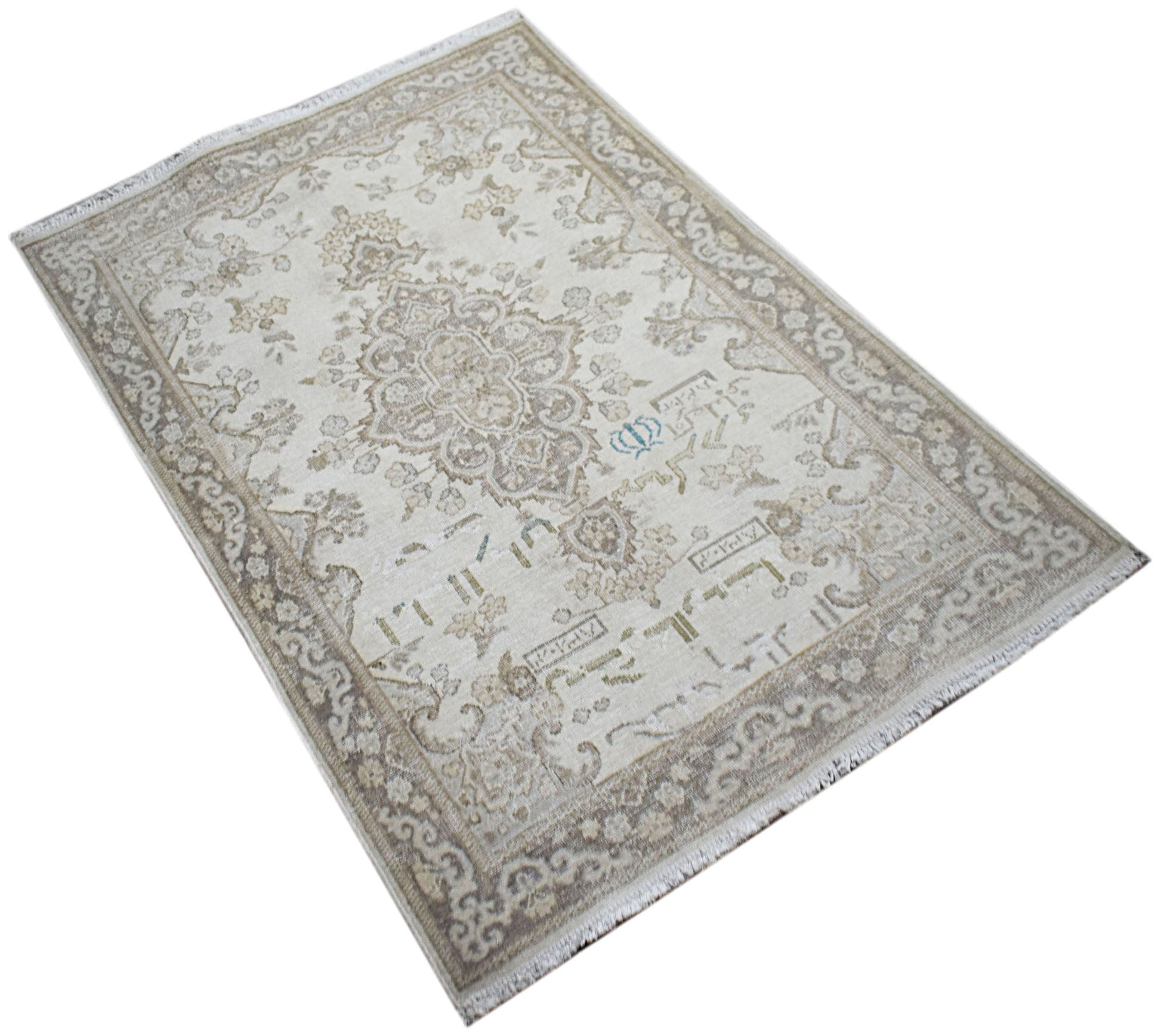 A vintage Persian Kerman rug featuring a central medallion and intricate floral patterns in beige.