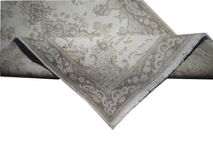 A vintage Persian Kerman rug with a beige floral pattern and a detailed central medallion.