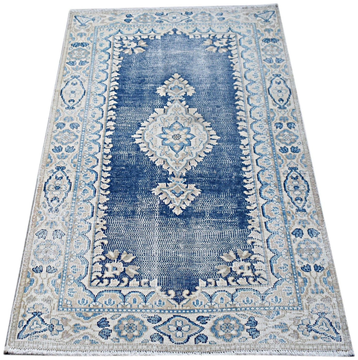 A vintage Persian Kerman rug featuring a central medallion and floral motifs in blue and beige.