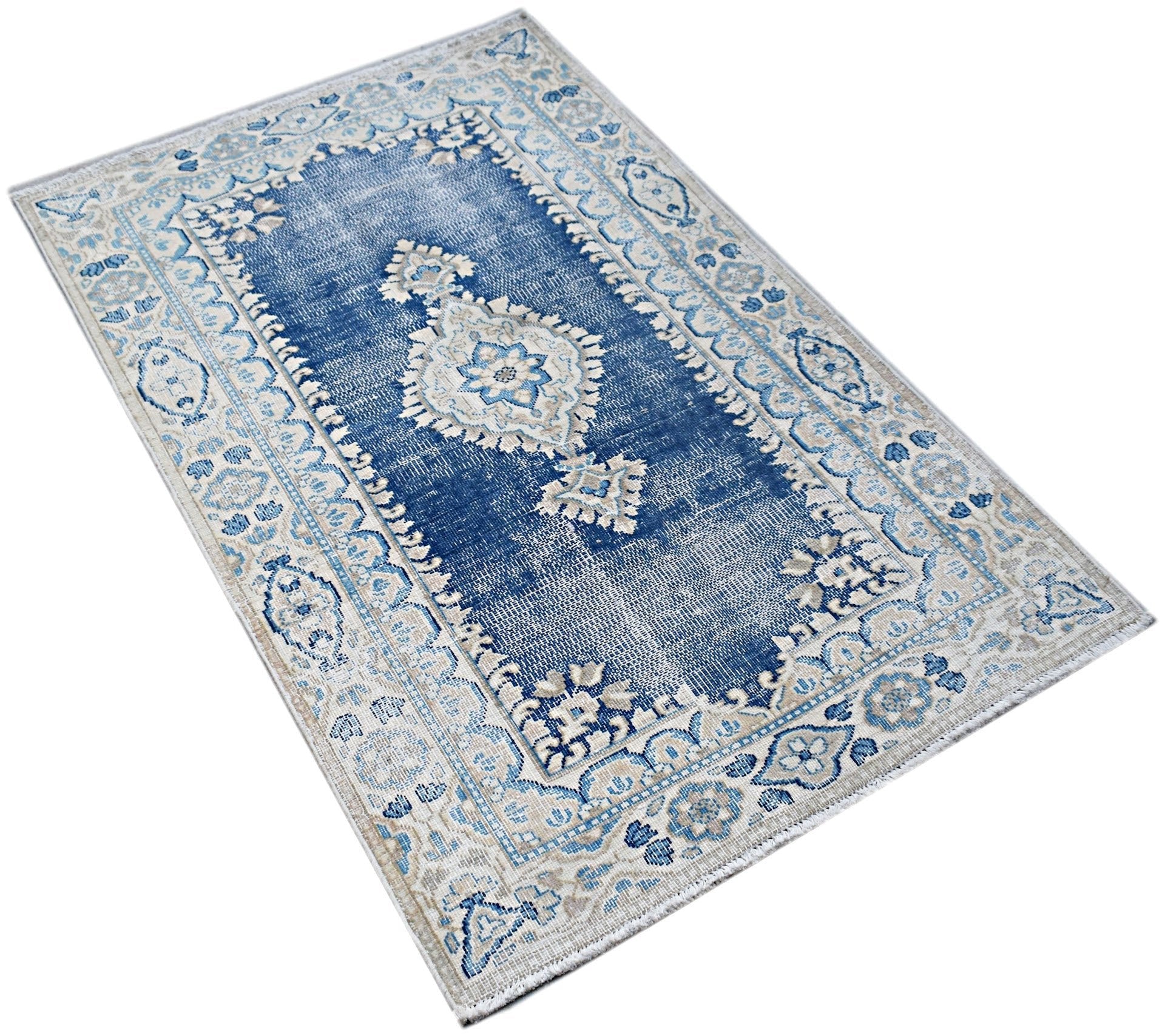 A vintage Persian Kerman rug featuring a central medallion and intricate floral patterns in blue.