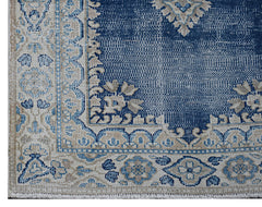 A vintage Persian Kerman rug featuring a blue field with intricate floral patterns and a border.