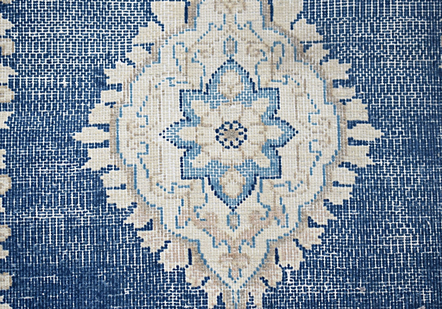 A vintage Persian Kerman rug featuring a central blue and beige floral medallion on a textured field.