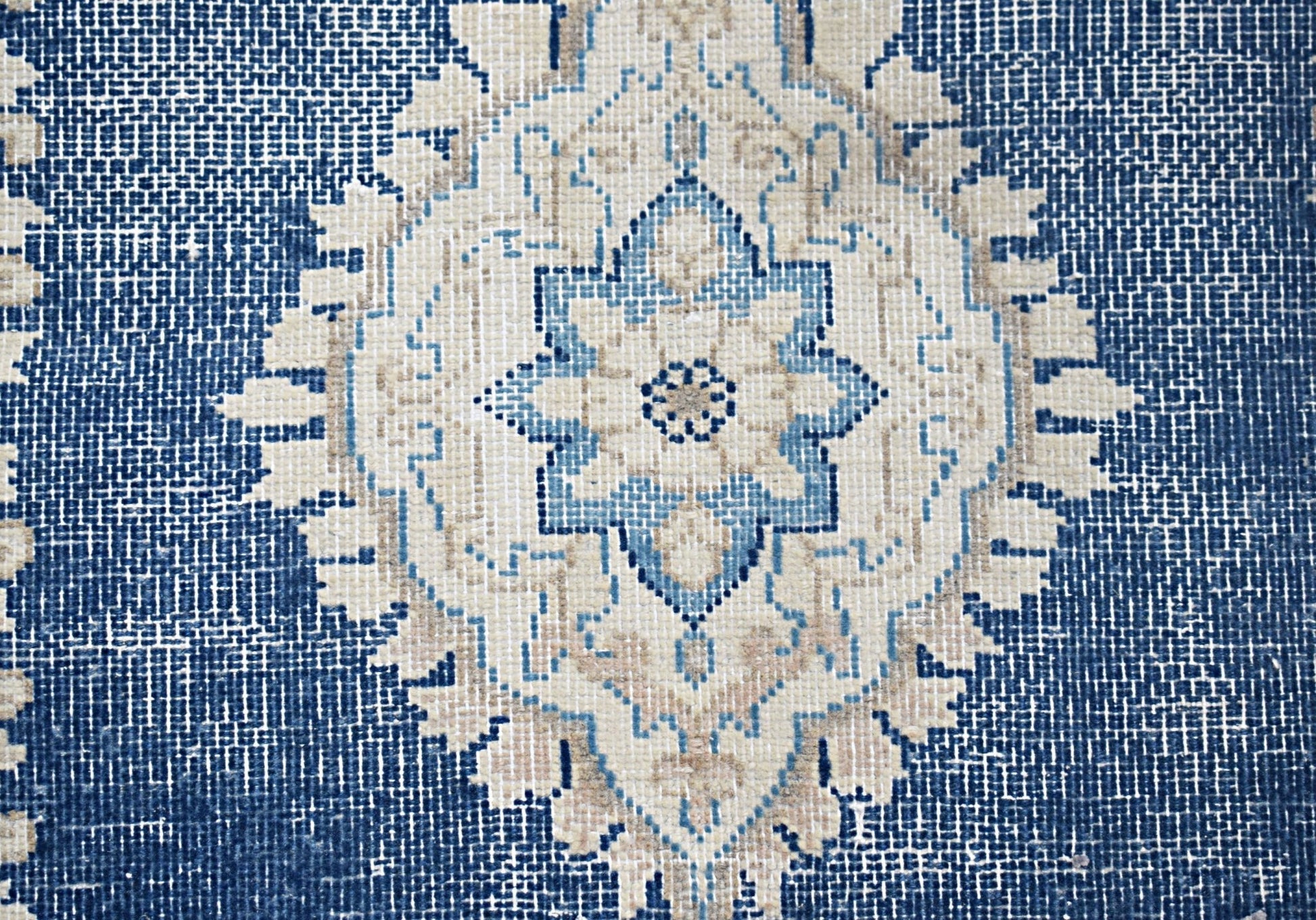 A vintage Persian Kerman rug featuring a central blue and beige floral medallion on a textured field.