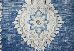 A vintage Persian Kerman rug featuring a central blue and beige floral medallion on a textured field.