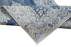A vintage Persian Kerman rug featuring a blue and beige floral medallion pattern.