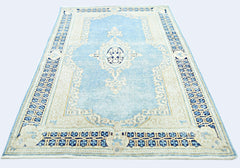 A vintage Persian Kerman rug featuring a central medallion and floral motifs in blue and cream.