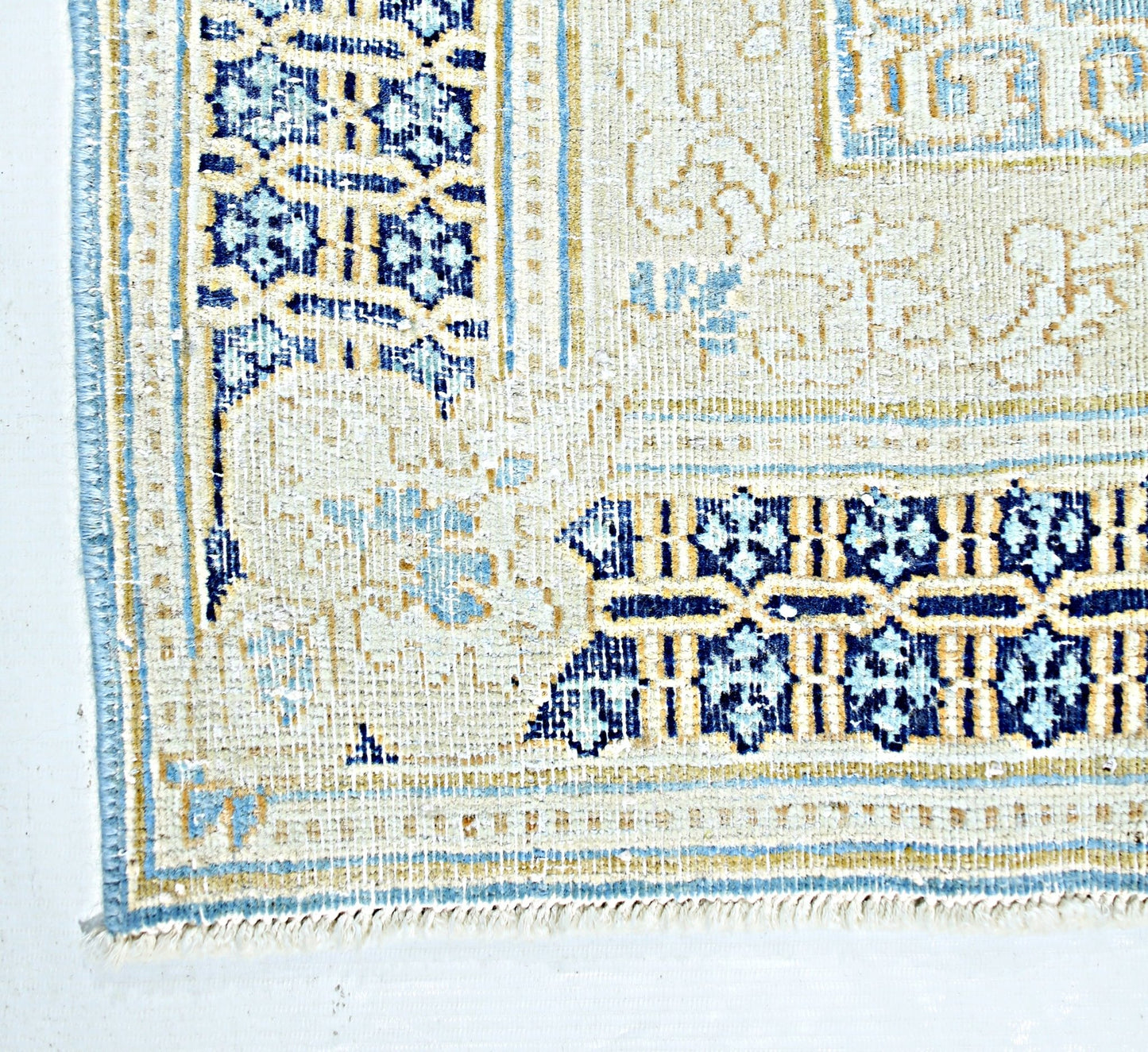 A vintage Persian Kerman rug featuring intricate blue and cream floral patterns and a fringed edge.