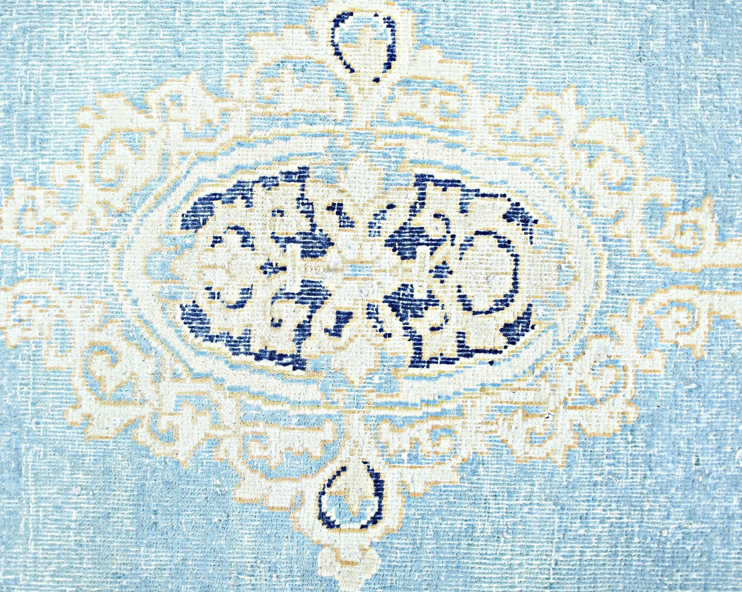 A vintage Persian Kerman rug featuring a central blue and cream floral medallion design.
