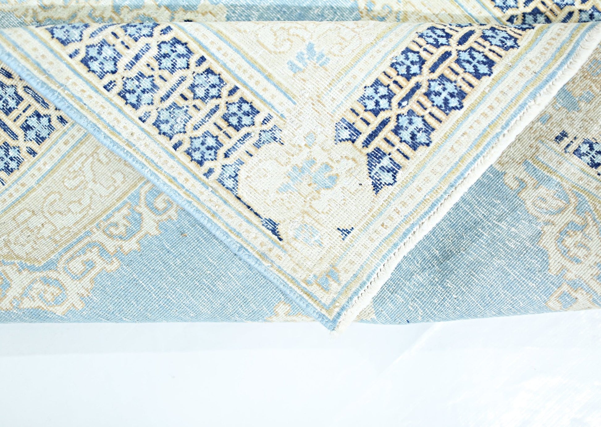 A folded vintage Persian Kerman rug featuring intricate blue and cream floral patterns.
