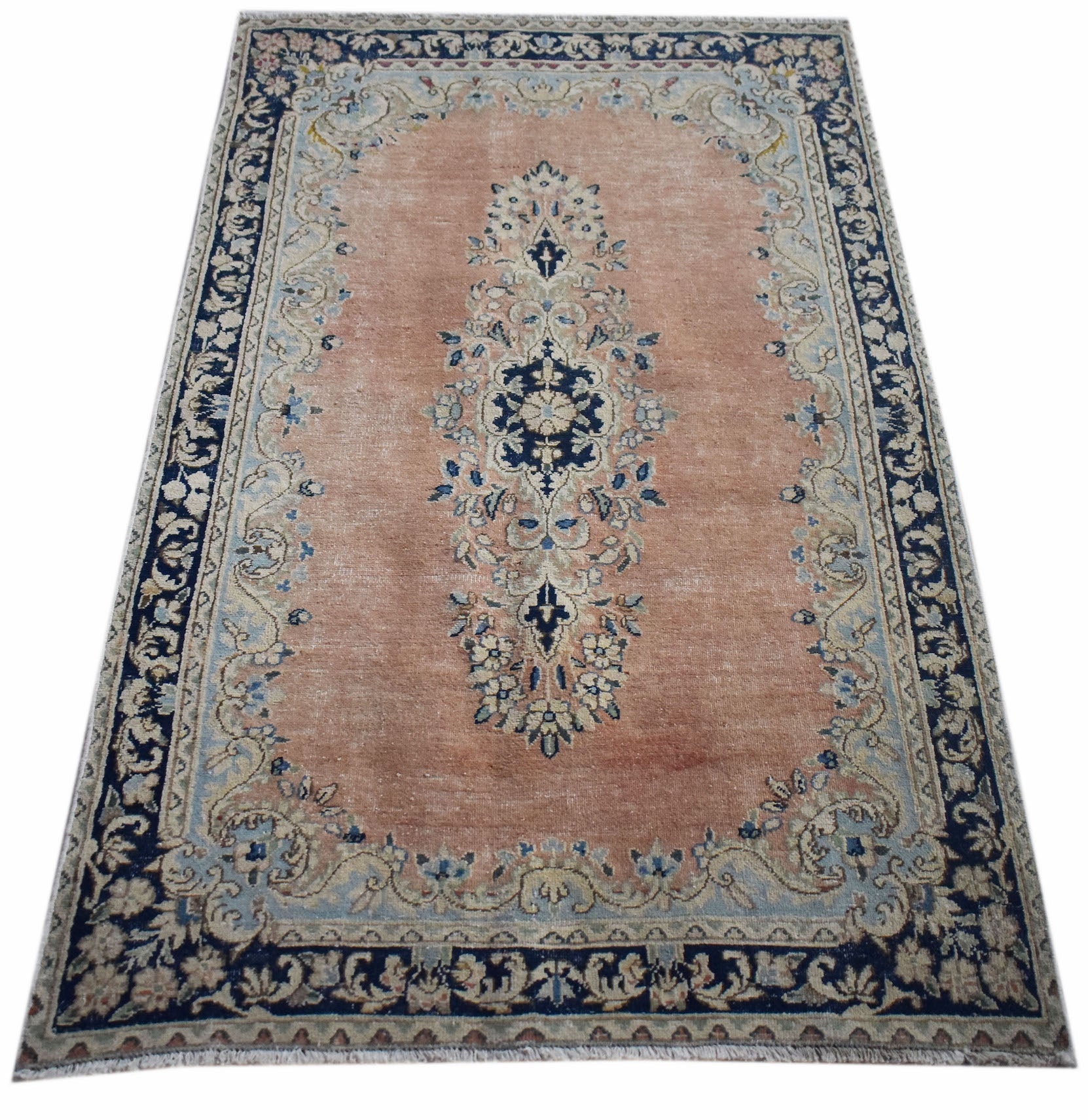 A vintage Persian Kerman rug featuring a central floral medallion on a soft peach field.