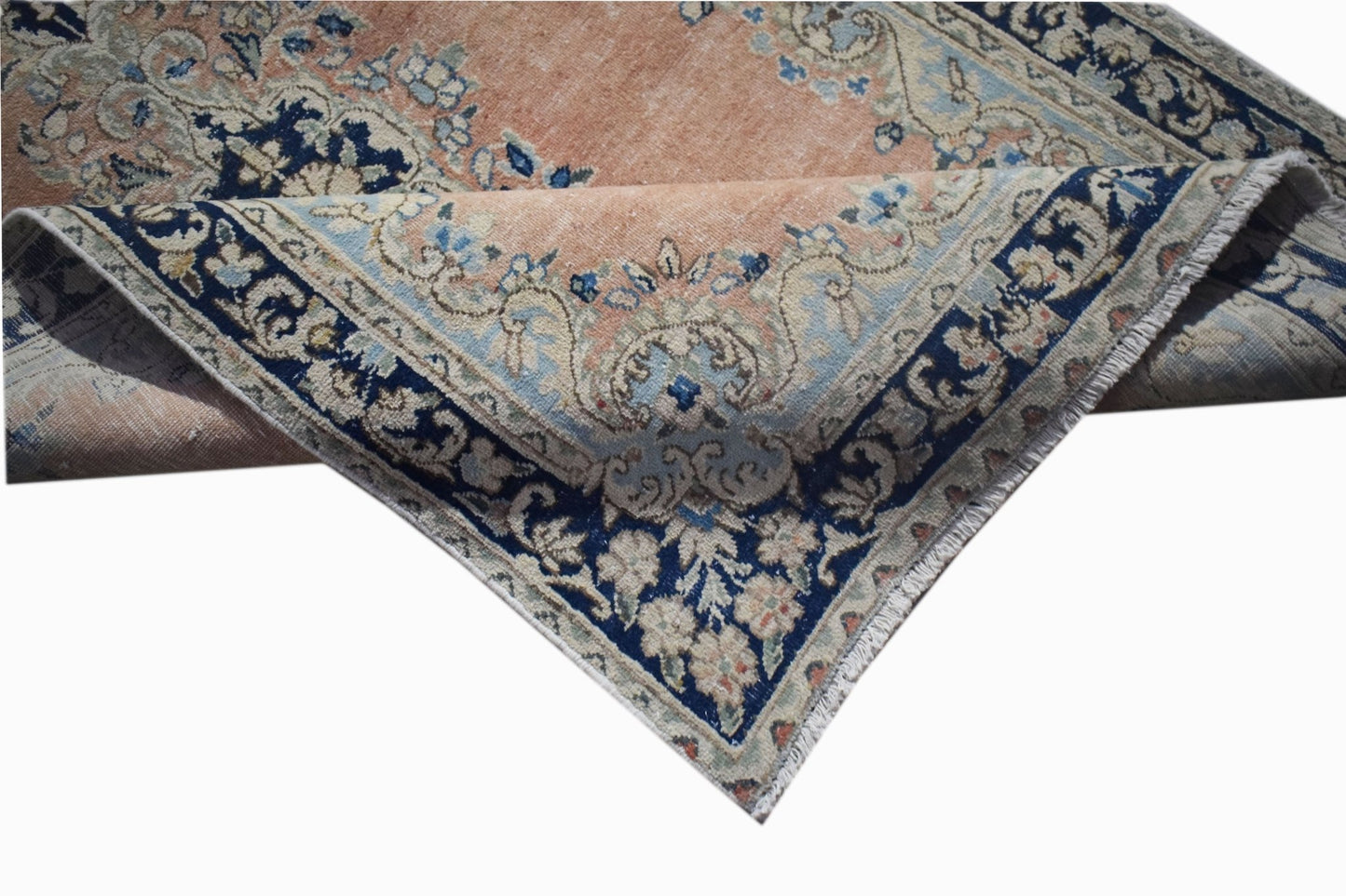 A vintage Persian Kerman rug featuring a floral medallion design in soft peach and blue tones.