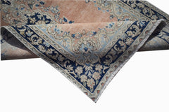 A vintage Persian Kerman rug featuring a floral medallion design in soft peach and blue tones.