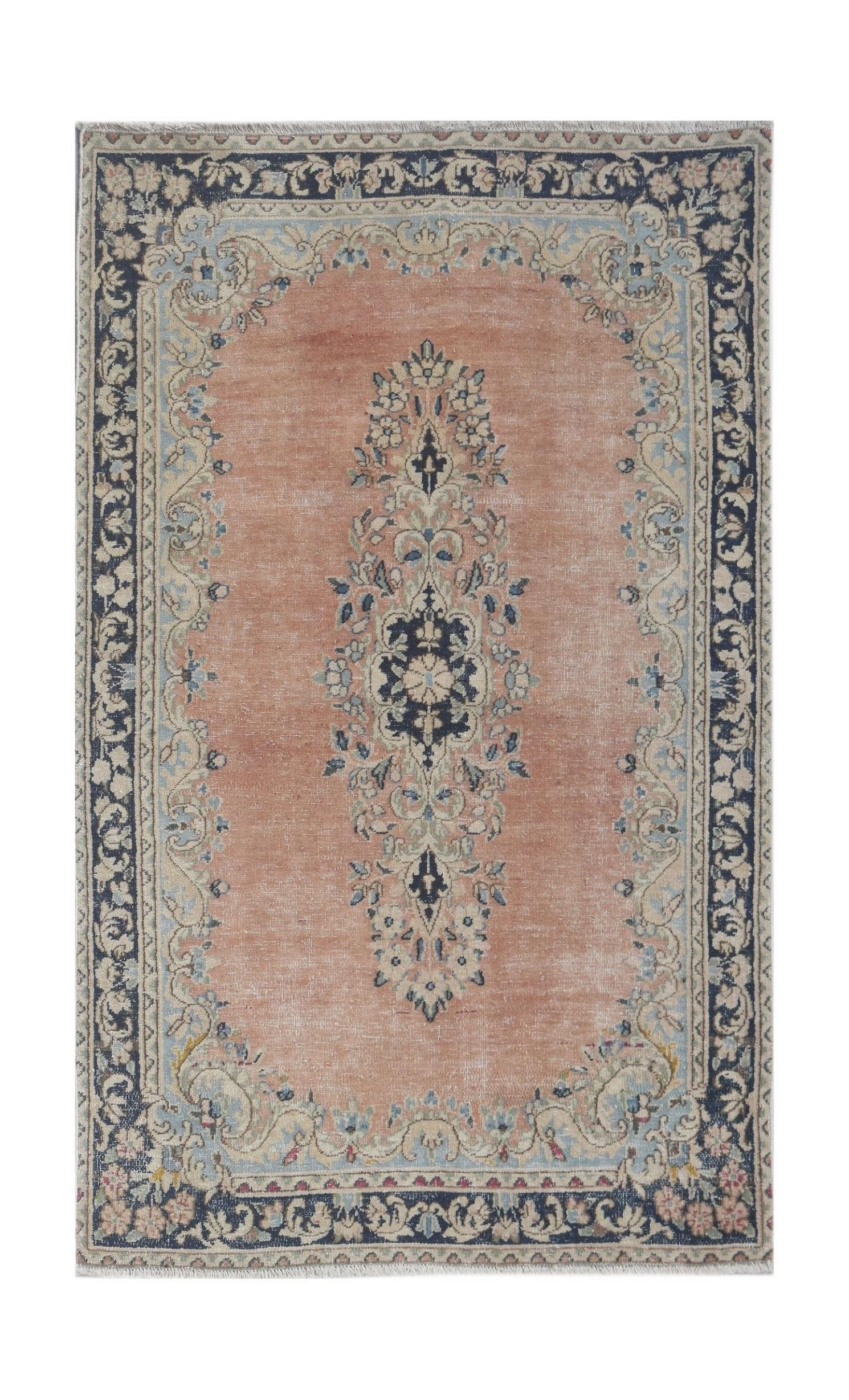 A vintage Persian Kerman rug featuring a central floral medallion on a soft peach field.