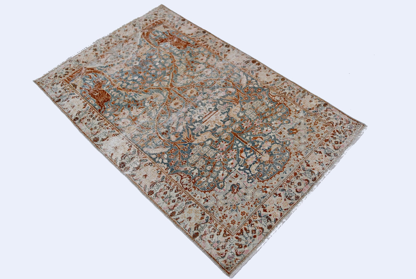 A vintage Persian Kerman rug featuring an intricate floral medallion design in muted tones.