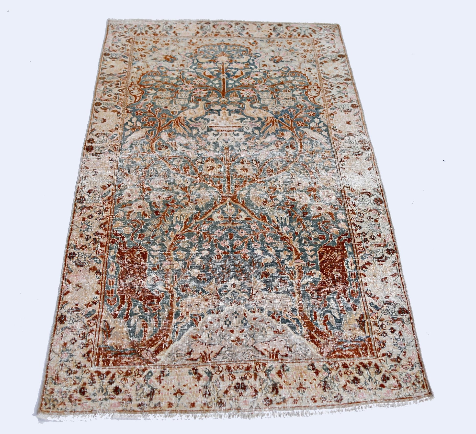 A vintage Persian Kerman rug featuring an intricate floral tree of life design in muted tones.