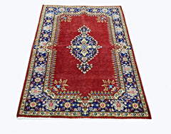 A vintage Persian Kerman rug featuring a central medallion on a red field with blue floral borders.