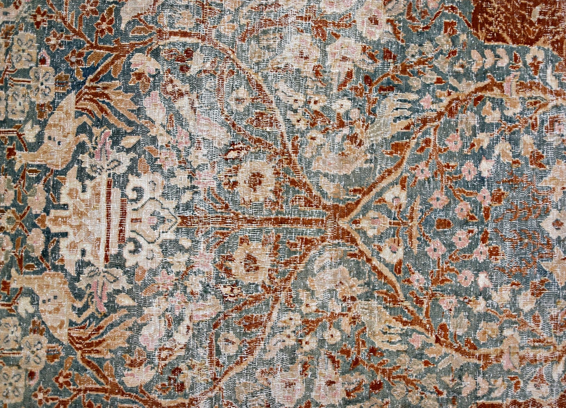 A vintage Persian Kerman rug featuring an intricate floral pattern in muted blue and rust tones.
