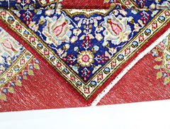A vintage Persian Kerman rug featuring a blue floral medallion on a red field.