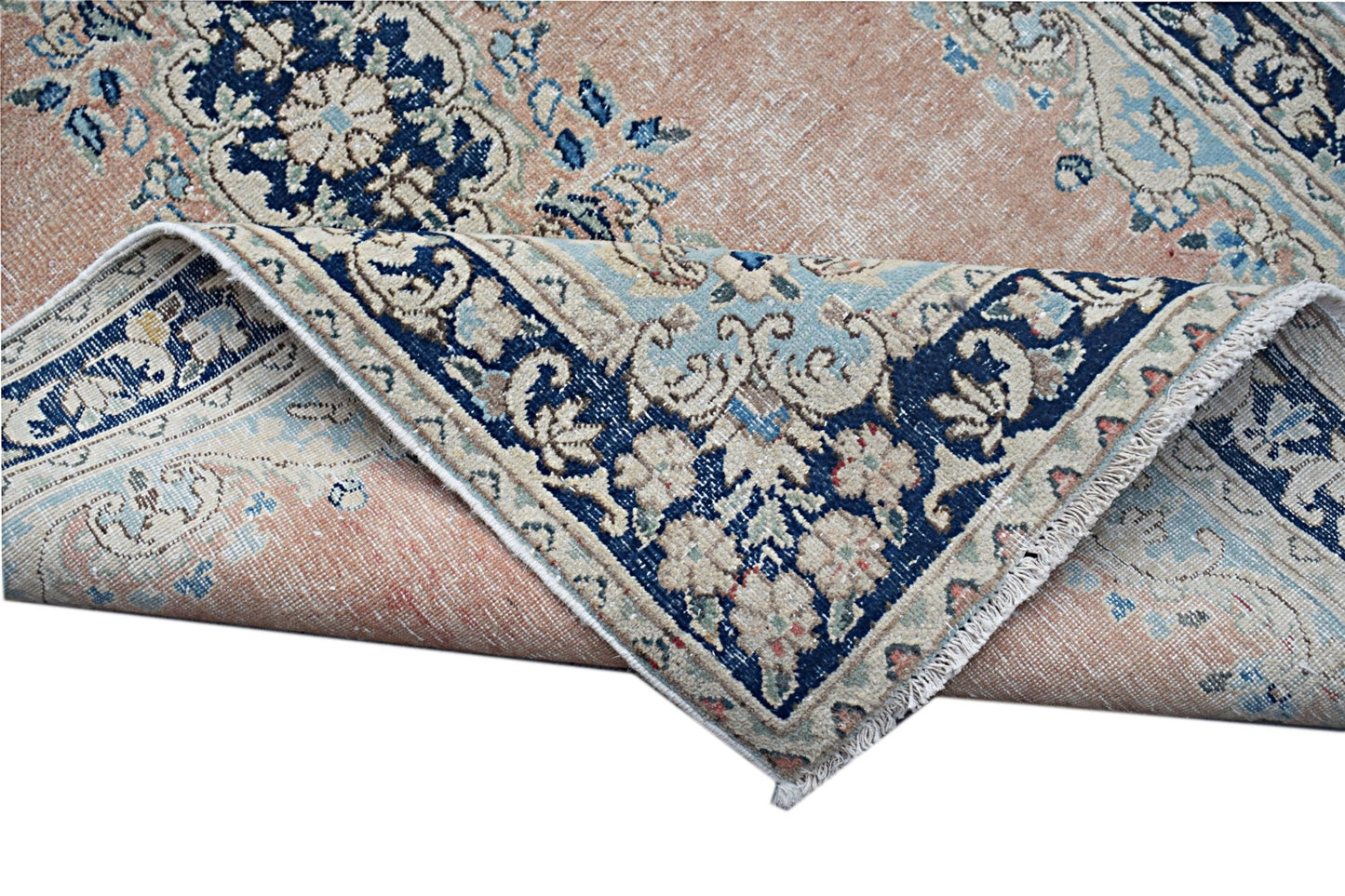 A vintage Persian Kerman rug featuring a floral medallion design in soft peach and blue tones.