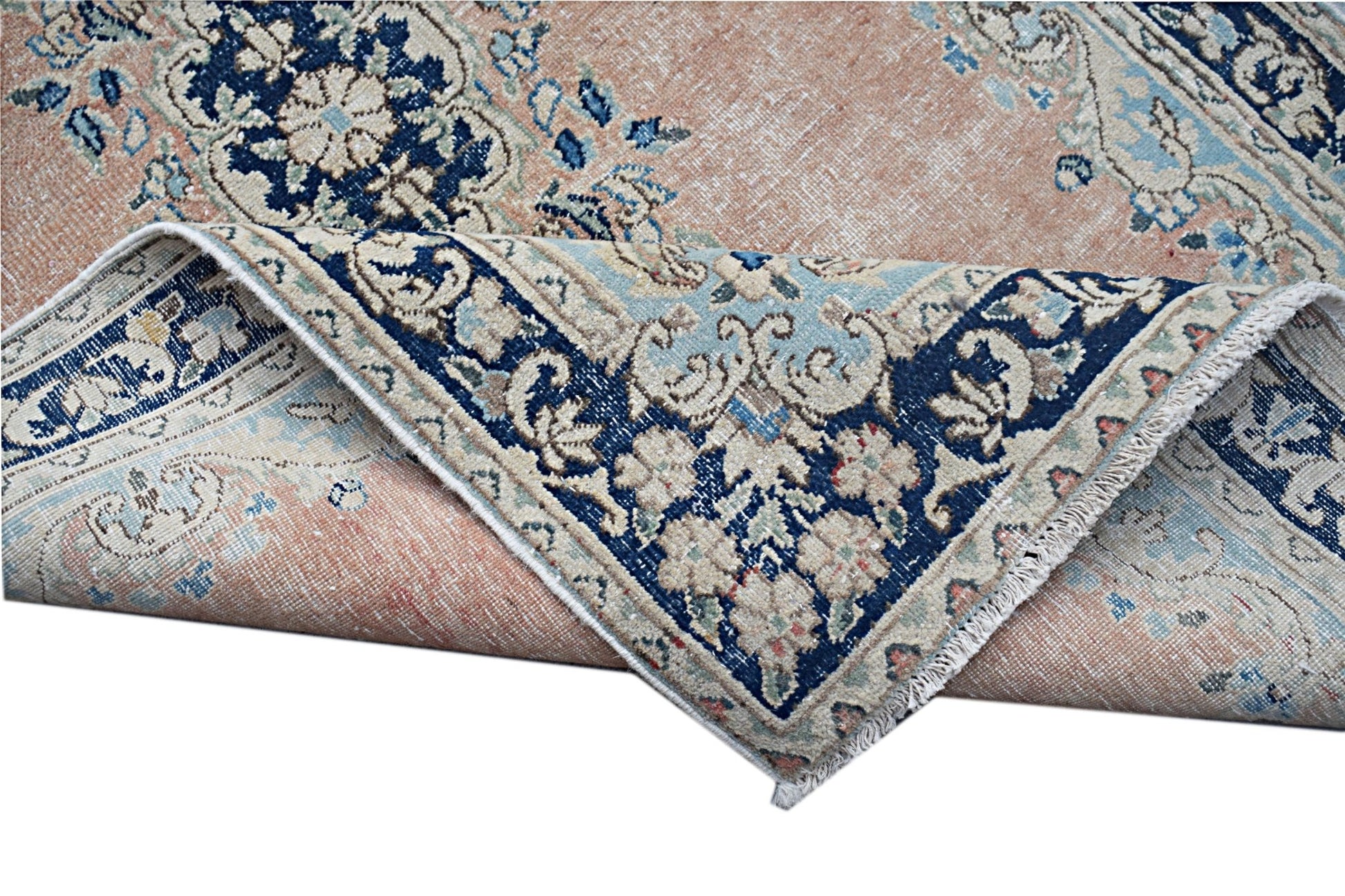 A vintage Persian Kerman rug featuring a floral medallion design in soft peach and blue tones.