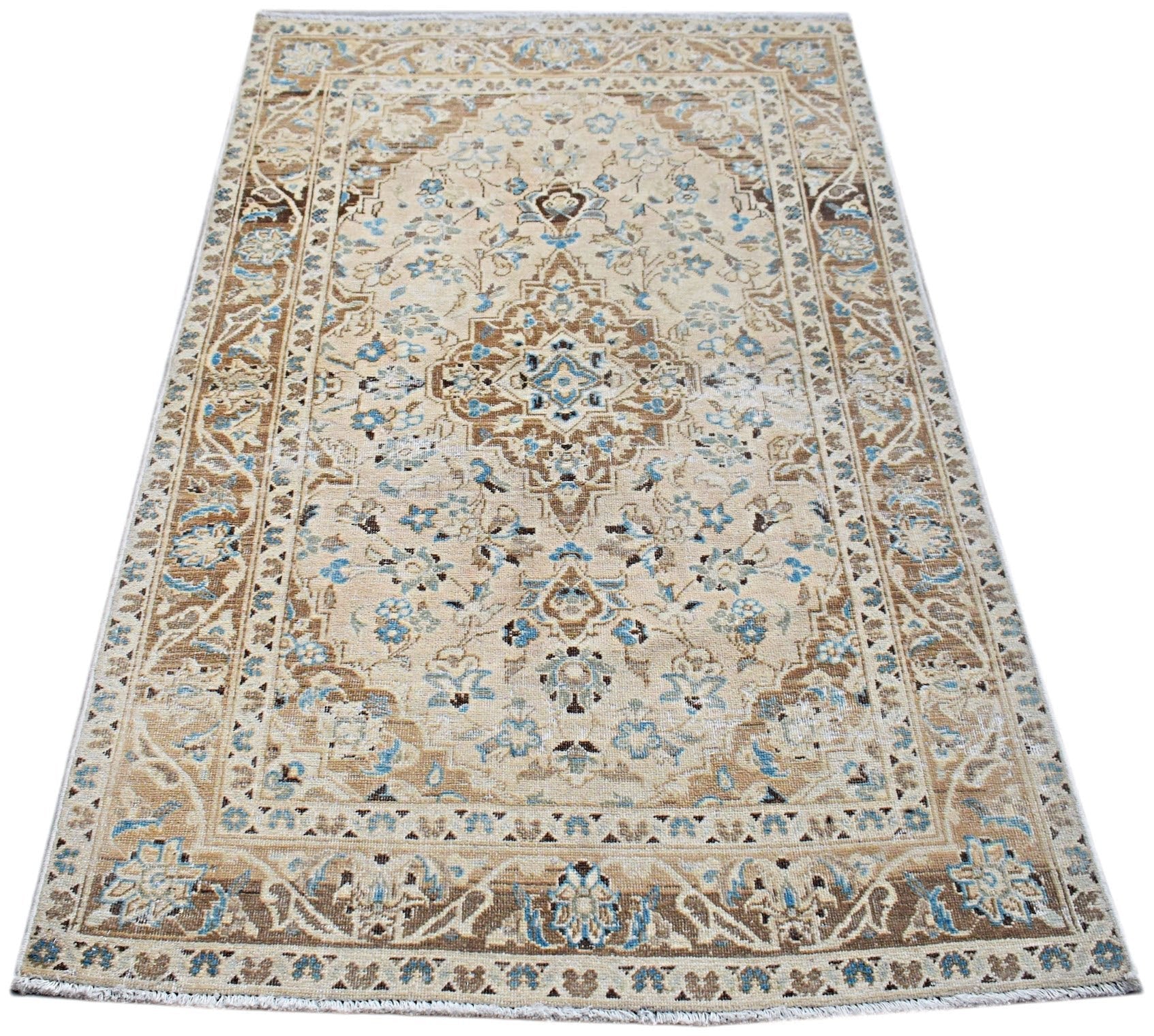 A vintage Persian Kerman rug featuring a central medallion and intricate floral patterns in blue and tan.