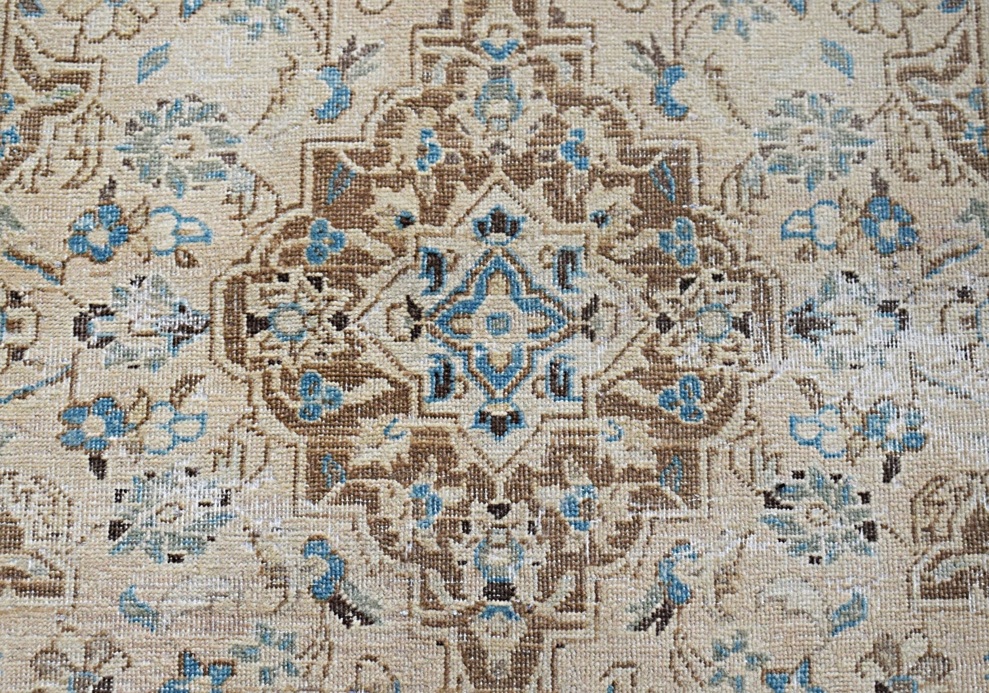 A vintage Persian Kerman rug featuring an intricate central medallion with blue and brown floral motifs.