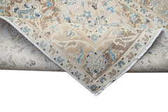 A vintage Persian Kerman rug featuring a beige field with intricate blue and brown floral patterns.