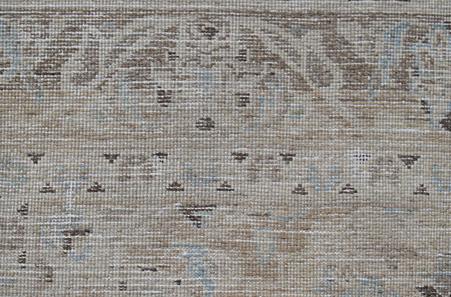 A close-up of a vintage Persian Kerman rug featuring intricate floral patterns in neutral tones.