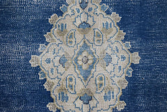 A vintage Persian Kerman rug featuring an intricate central medallion in blue and cream tones.