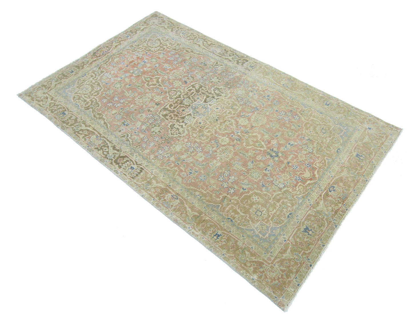 A vintage handmade Persian rug featuring a faded floral pattern in muted pink and beige tones.