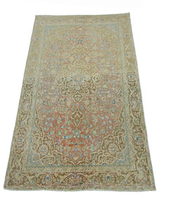 A vintage handmade Persian rug featuring a floral pattern in muted pink, beige, and blue tones.
